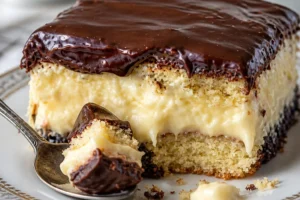 Delicious Boston Cream Poke Cake with yellow cake, vanilla pudding, and chocolate ganache.
