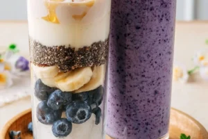 Creamy blueberry cheesecake smoothie in a glass with blueberries on top.