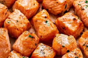 Crispy air fryer salmon bites served on a plate with dipping sauce.