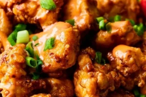 Healthy Bang Bang Chicken dish garnished with fresh herbs and vegetables.