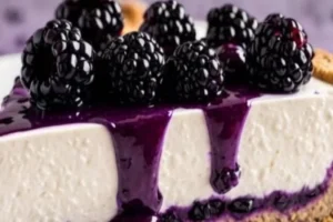 Slice of Blackberry Velvet Cheesecake topped with fresh blackberries